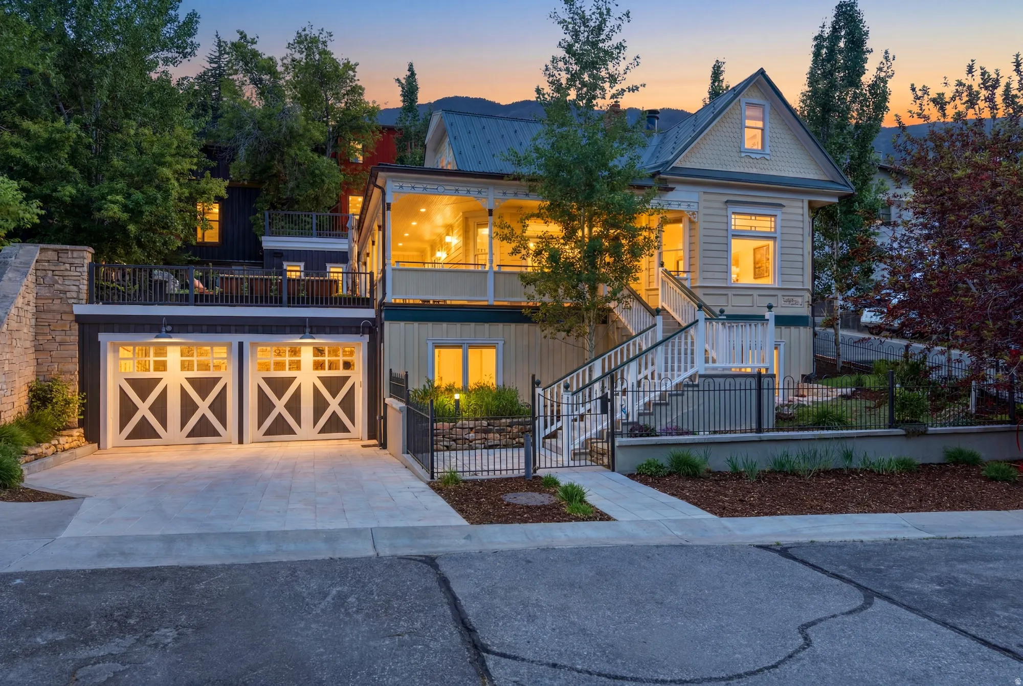 Multi-level property featuring a two-car garage with carriage-style doors, a concrete driveway, and a stone retaining wall