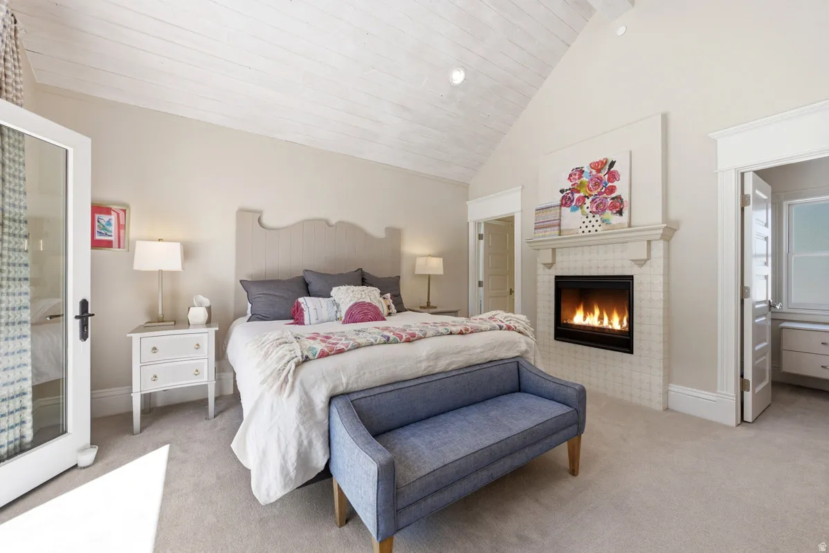 Vaulted ceiling with white wood-finish planks, recessed lighting, and a prominent fireplace featuring a tile surround and mantle