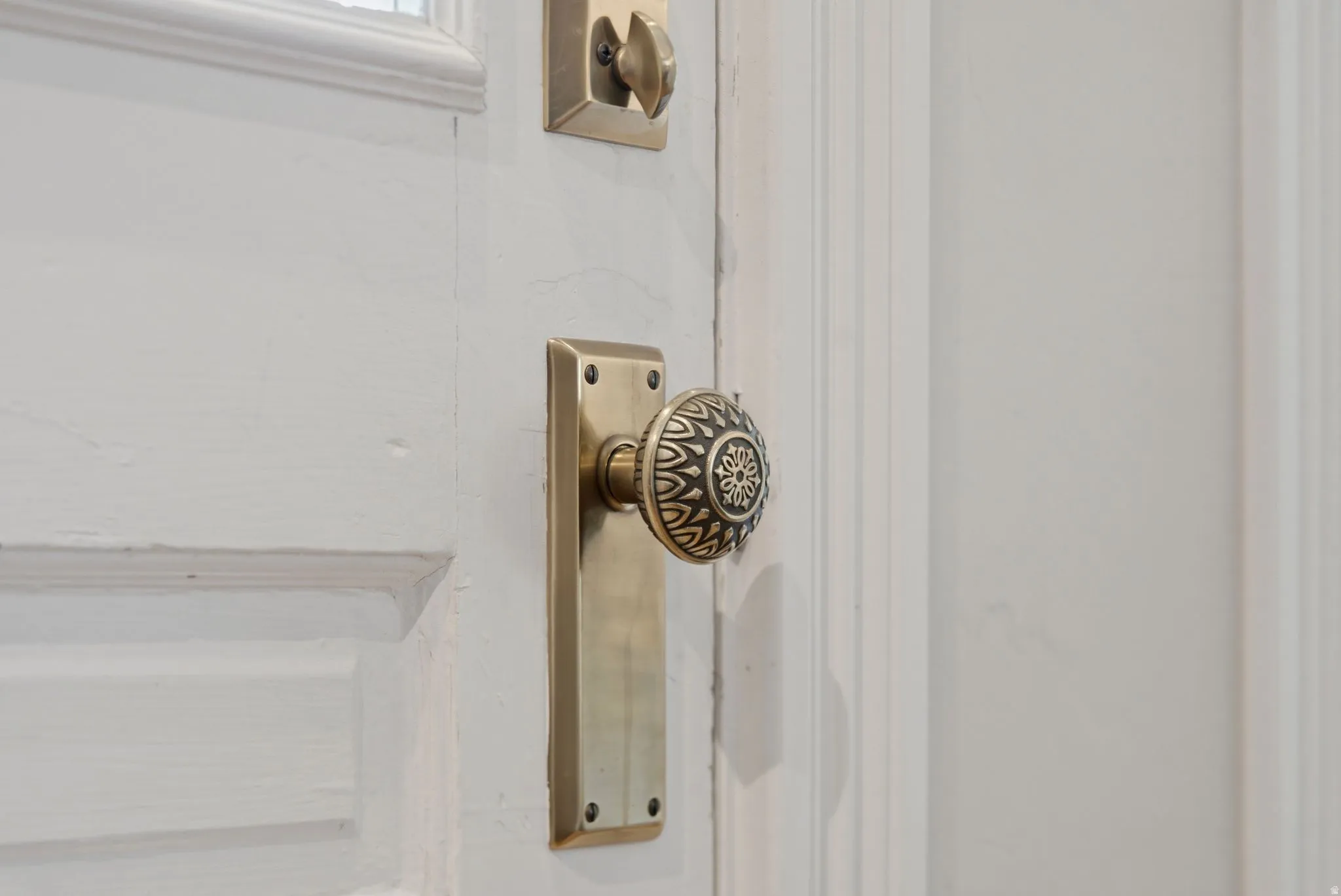 White paneled door with an ornate brass doorknob and matching escutcheon plate