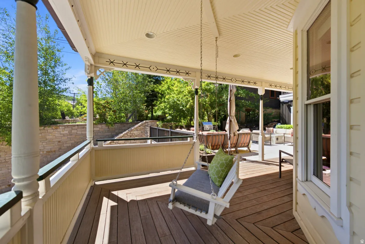 Covered porch featuring a swing and wood-finish flooring with a chevron pattern