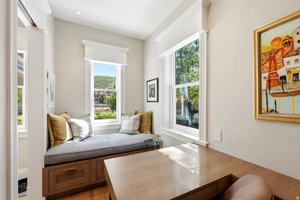 Integrated window seat with built-in storage drawers, double-hung windows, recessed lighting, and light wood-finish built-in desk