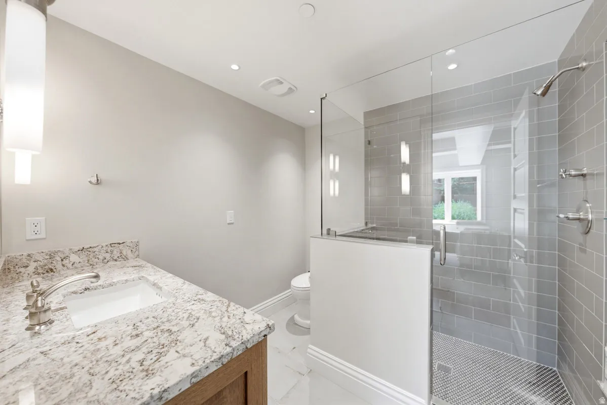 Modern bathroom featuring a wood-finish vanity with a granite countertop, undermount sink, and brushed nickel fixtures