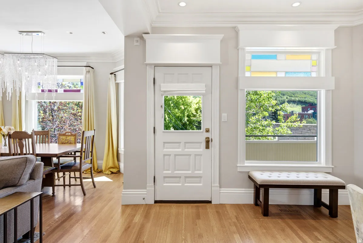 Entryway with wood-finish flooring featuring an ornate paneled door and window with decorative stained glass