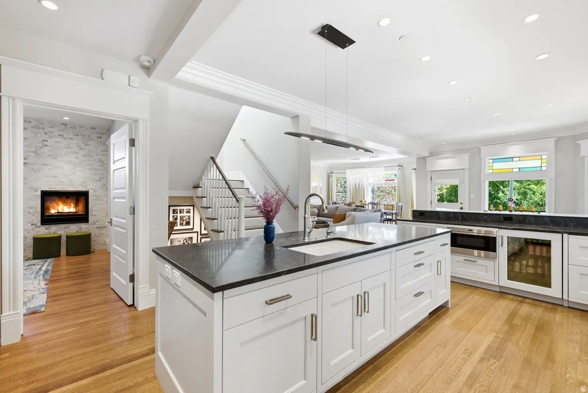 Kitchen island featuring a built-in sink, ample white cabinetry, and dark countertops