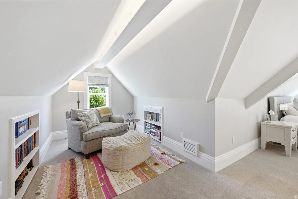 Gable roofline with exposed beams, built-in shelving, window with natural light, and neutral wall finishes