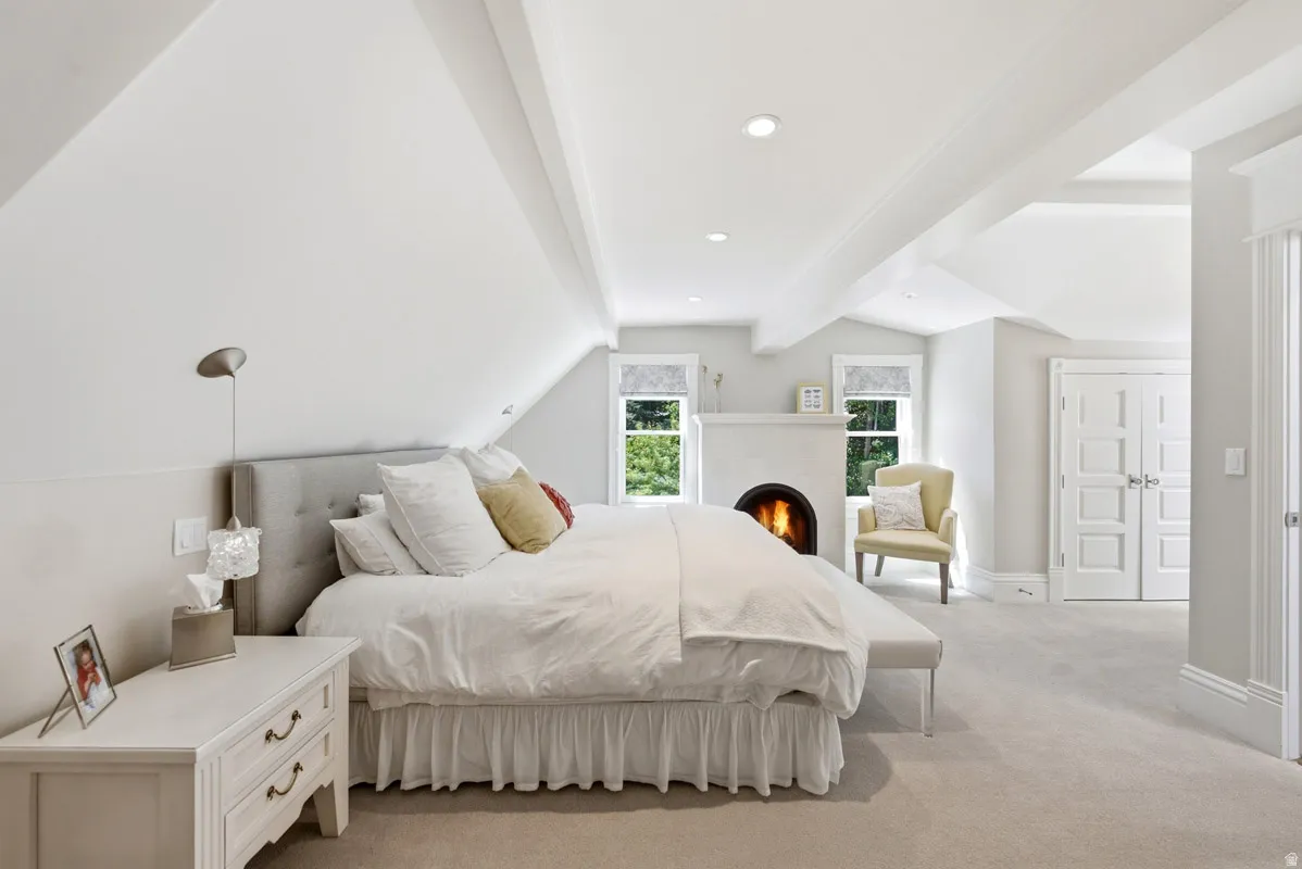 Vaulted ceiling with exposed beams, recessed lighting, and a built-in fireplace