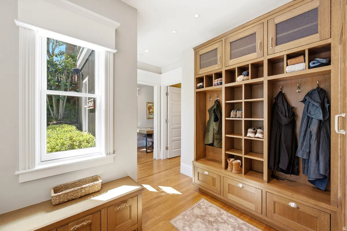 Entryway mudroom featuring built-in wood cabinetry with integrated seating and storage, hardwood flooring, and a window overlooking exterior landscaping