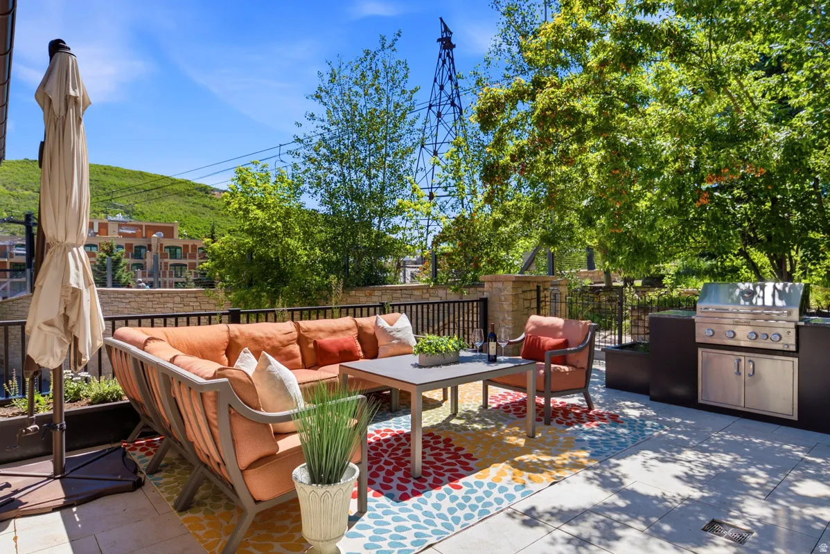 Spacious outdoor patio featuring a built-in grill station, ample seating area, and mature landscaping