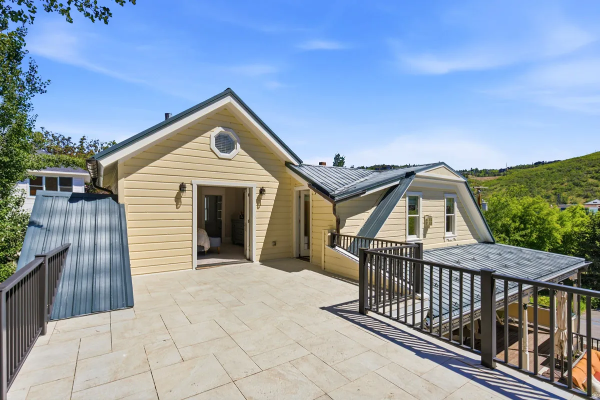 Expansive outdoor patio featuring light-toned tile flooring, metal railings, and direct access to an interior space via French doors