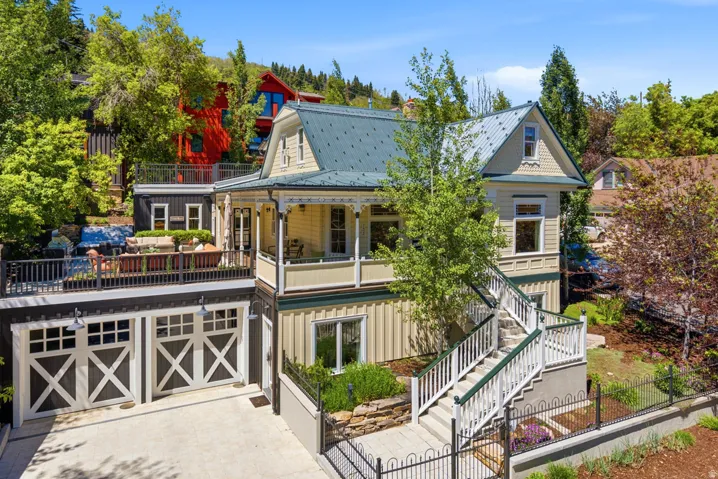Victorian-inspired residence featuring a covered front porch, an upper-level patio, and a two-car garage with carriage-style doors