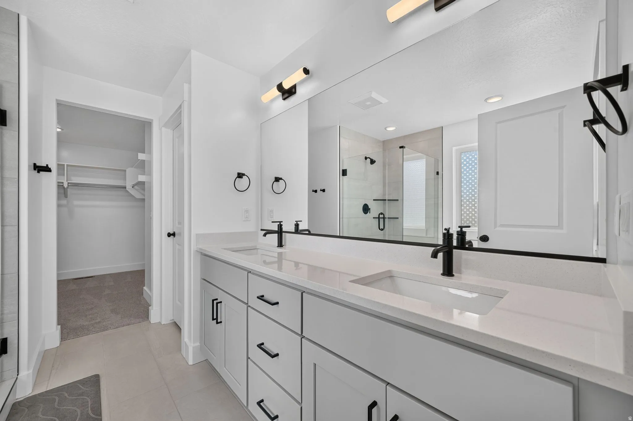 Dual sink vanity with white quartz countertops, integrated rectangular sinks, and matte black fixtures