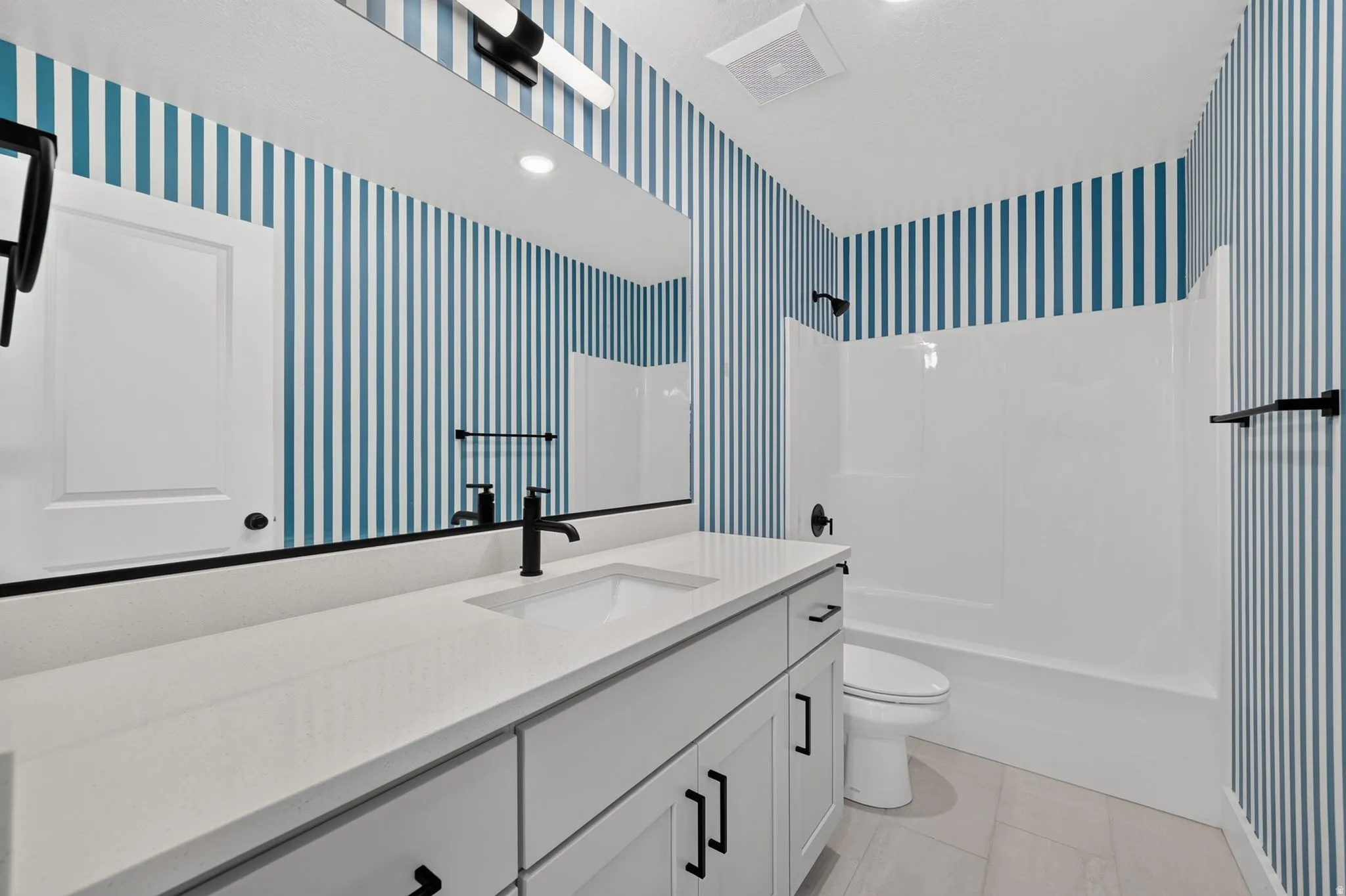 Bathroom vanity featuring a quartz countertop, integrated sink, and matte black fixtures