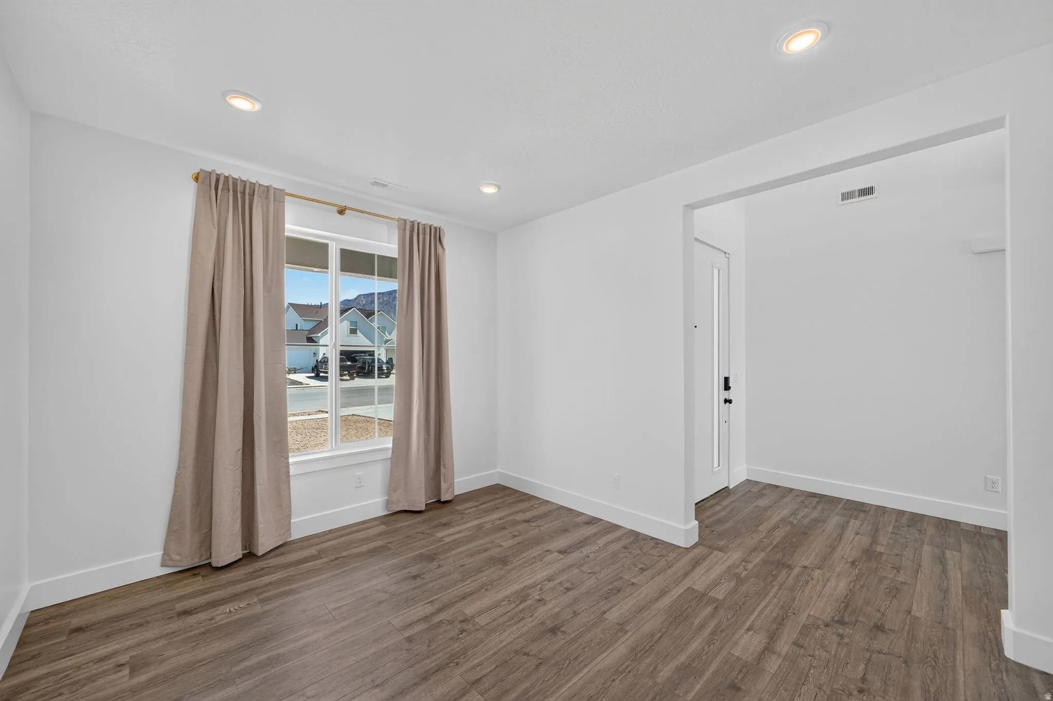 Spacious room featuring wood-finish flooring, recessed lighting, and a large window