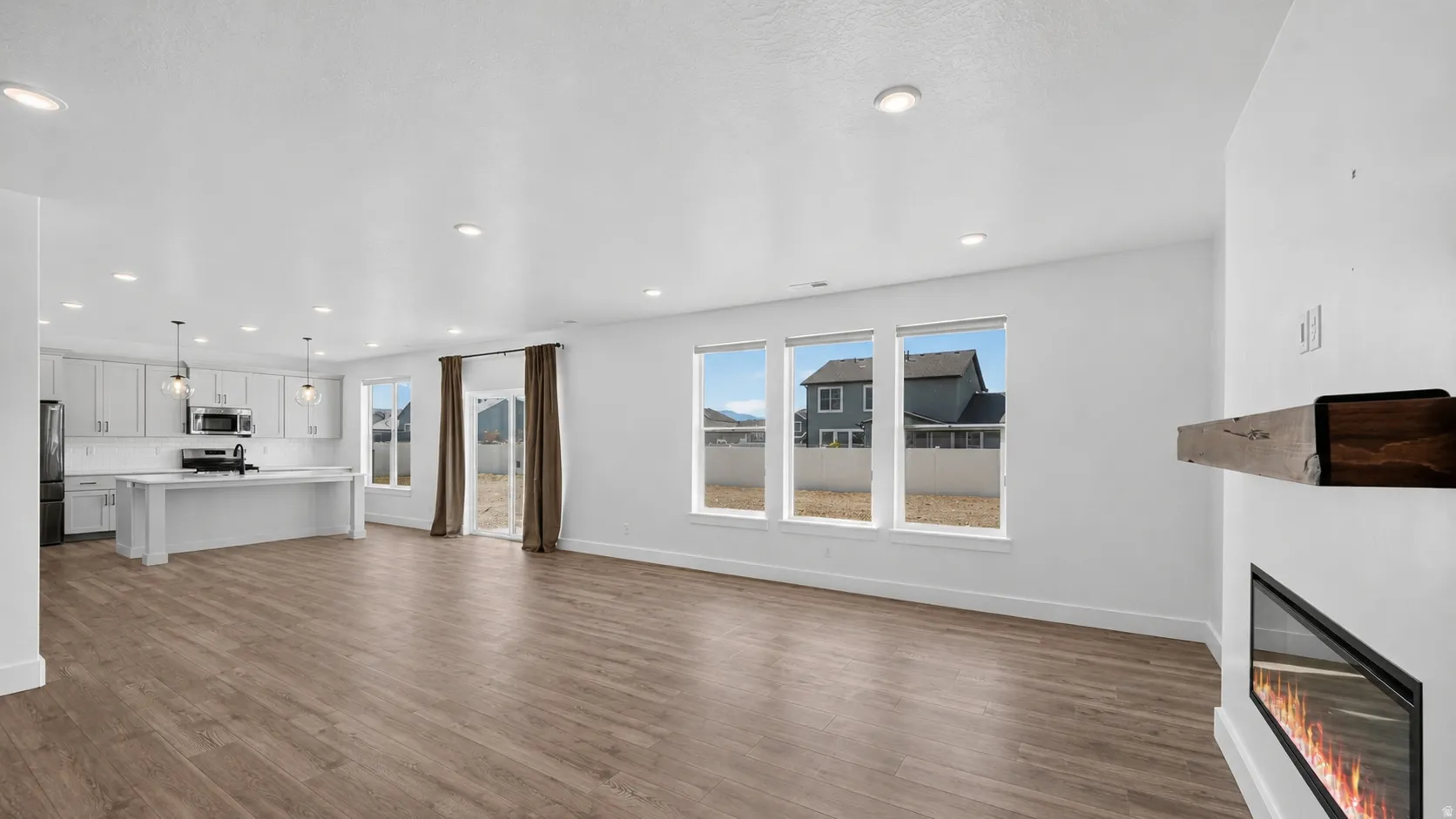 Open-concept living area featuring wood-finish flooring, recessed lighting, and white baseboards