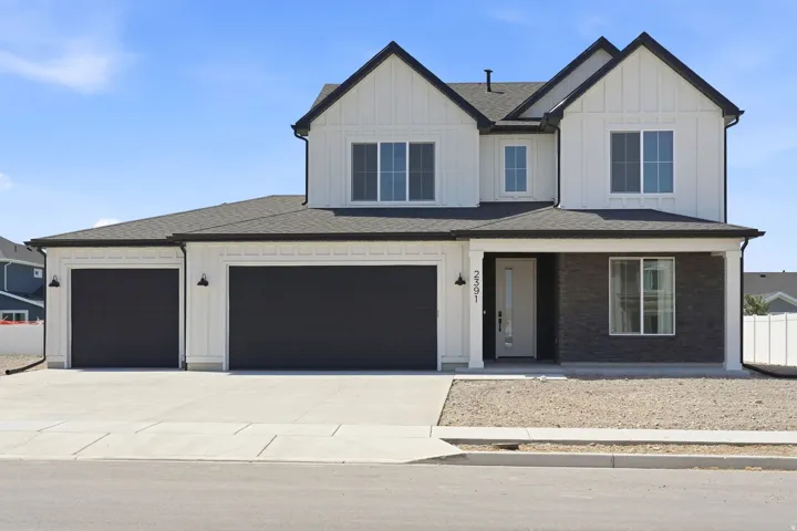 Modern two-story residence with a multi-gabled roofline and a combination of white vertical siding and dark brick accents