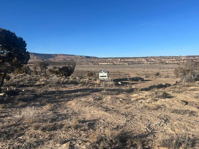 Expansive arid landscape featuring natural vegetation and distant mesa formations