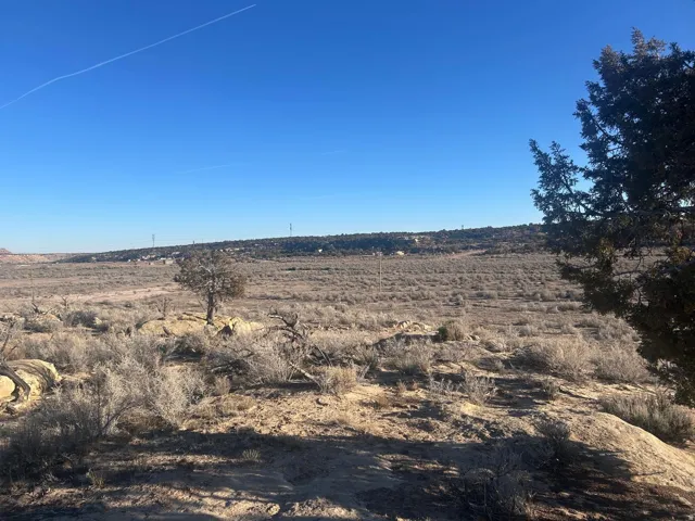 Expansive desert landscape featuring natural rock formations, scattered brush, and distant horizon
