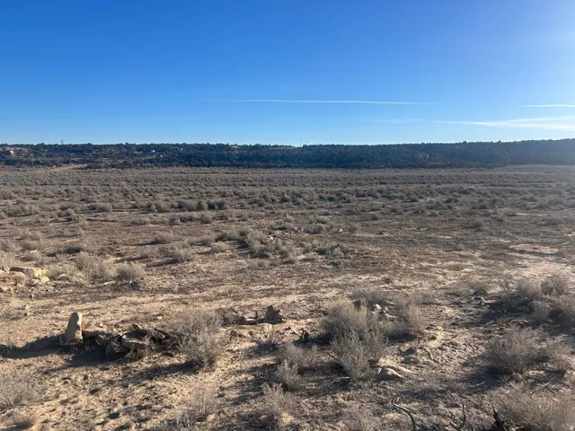 Expansive undeveloped land featuring natural terrain with sparse vegetation under a clear sky