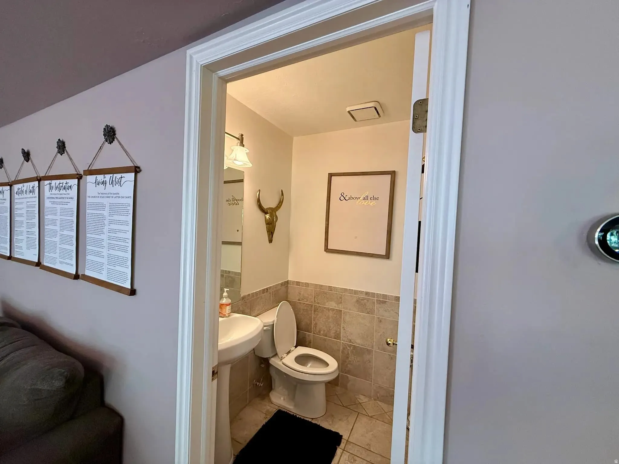 Powder room featuring a pedestal sink, toilet, and tiled walls and flooring