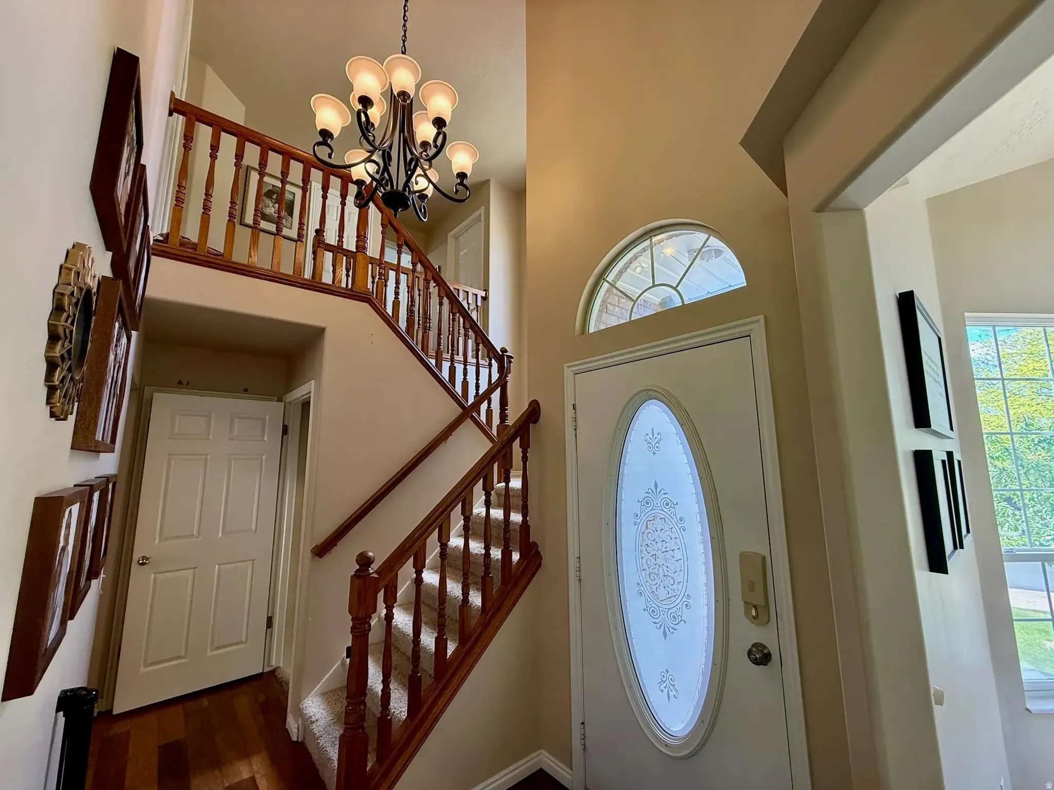 Two-story entryway featuring a decorative oval-lite door and transom window