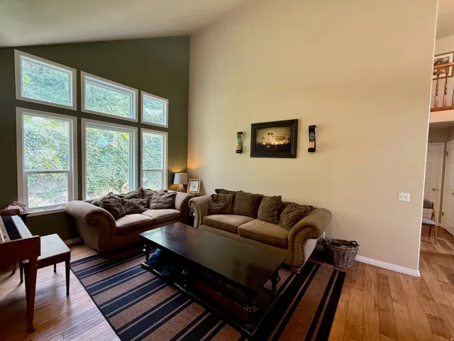 Living area featuring a high ceiling, a multi-pane window configuration, and wood-finish flooring