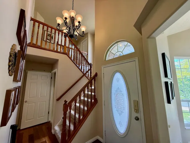 Two-story entryway featuring a decorative oval-lite door and transom window
