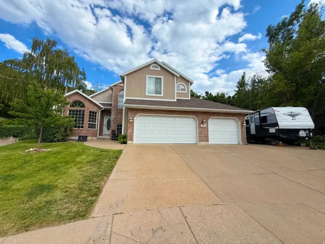 Brick and stucco exterior featuring an arched entryway and a prominent two-car garage