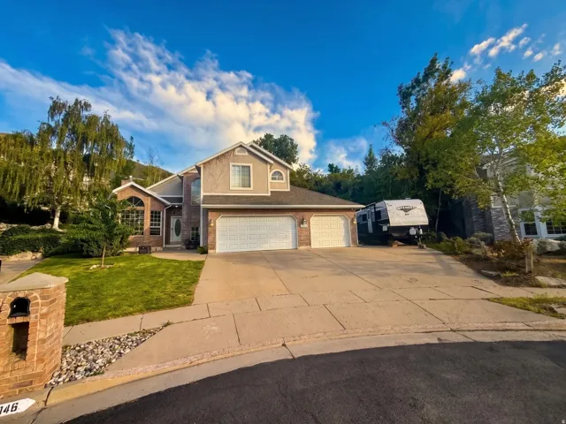 Two-story residence featuring a brick and stucco exterior, a two-car garage, and an additional paved parking area