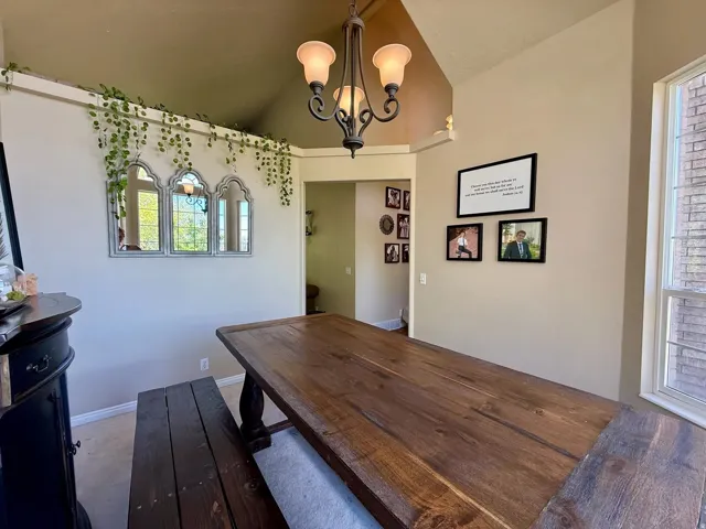 Dining area featuring a vaulted ceiling and an iron chandelier with frosted glass shades