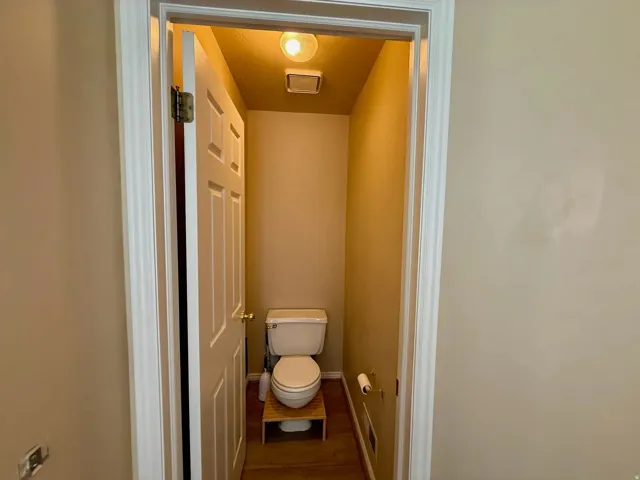 Powder room featuring a standard white toilet and wood-finish flooring