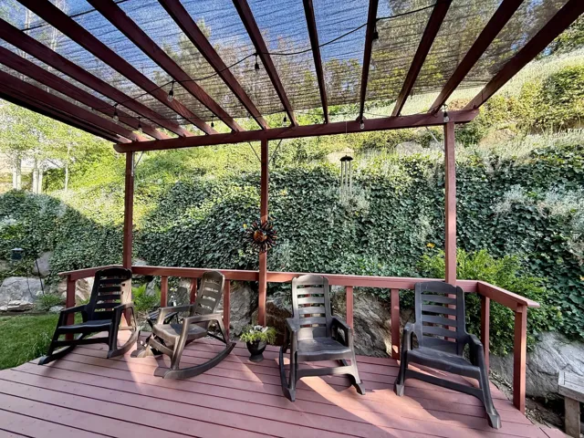 Outdoor deck featuring a wood pergola with a black shade cover and string lighting