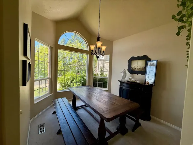 Inviting dining area featuring an arched window, multiple casement windows with grid patterns, vaulted ceilings, and a chandelier