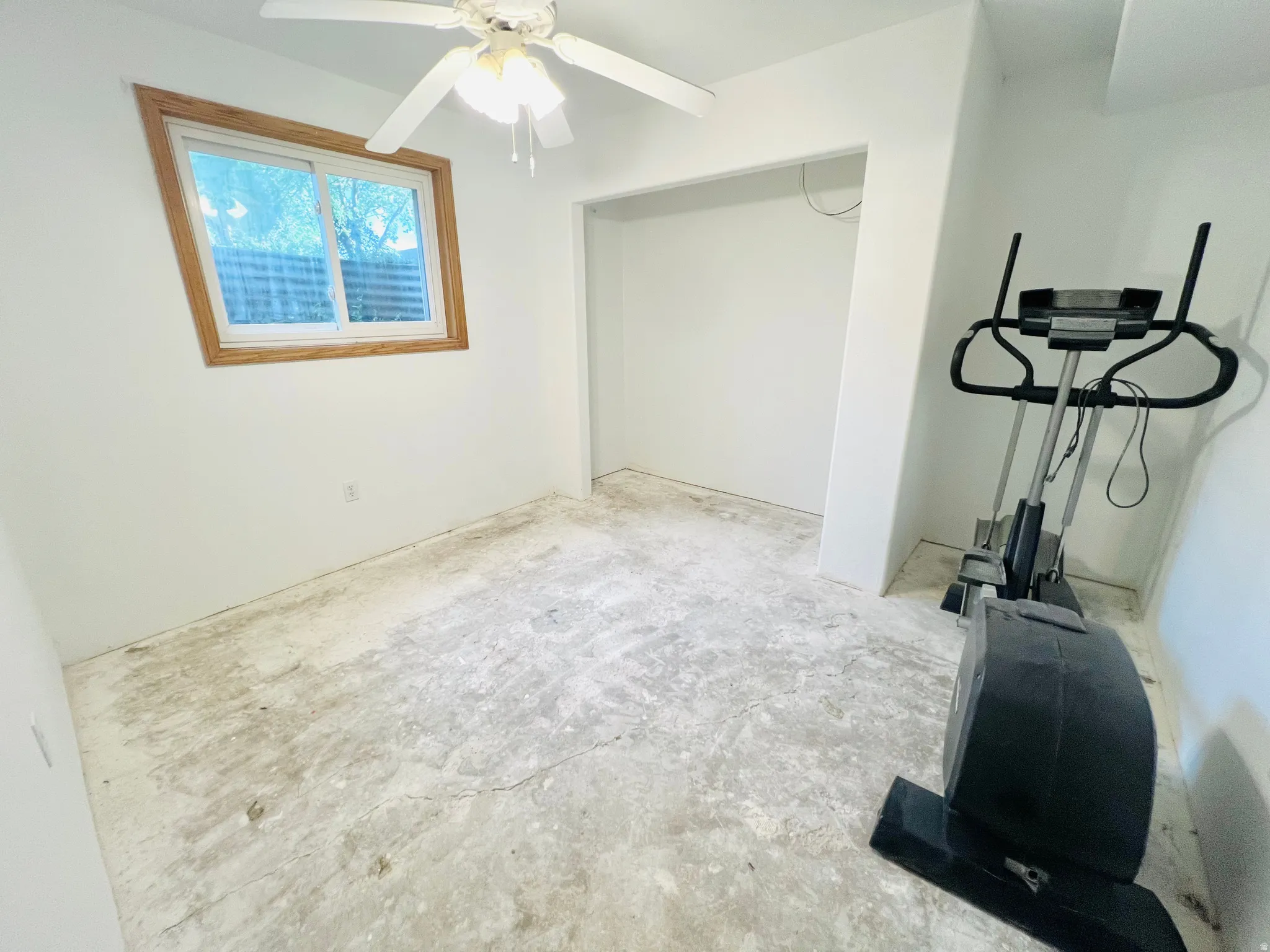 Room featuring a wood-trimmed window, a ceiling fan with light fixture, and a recessed alcove