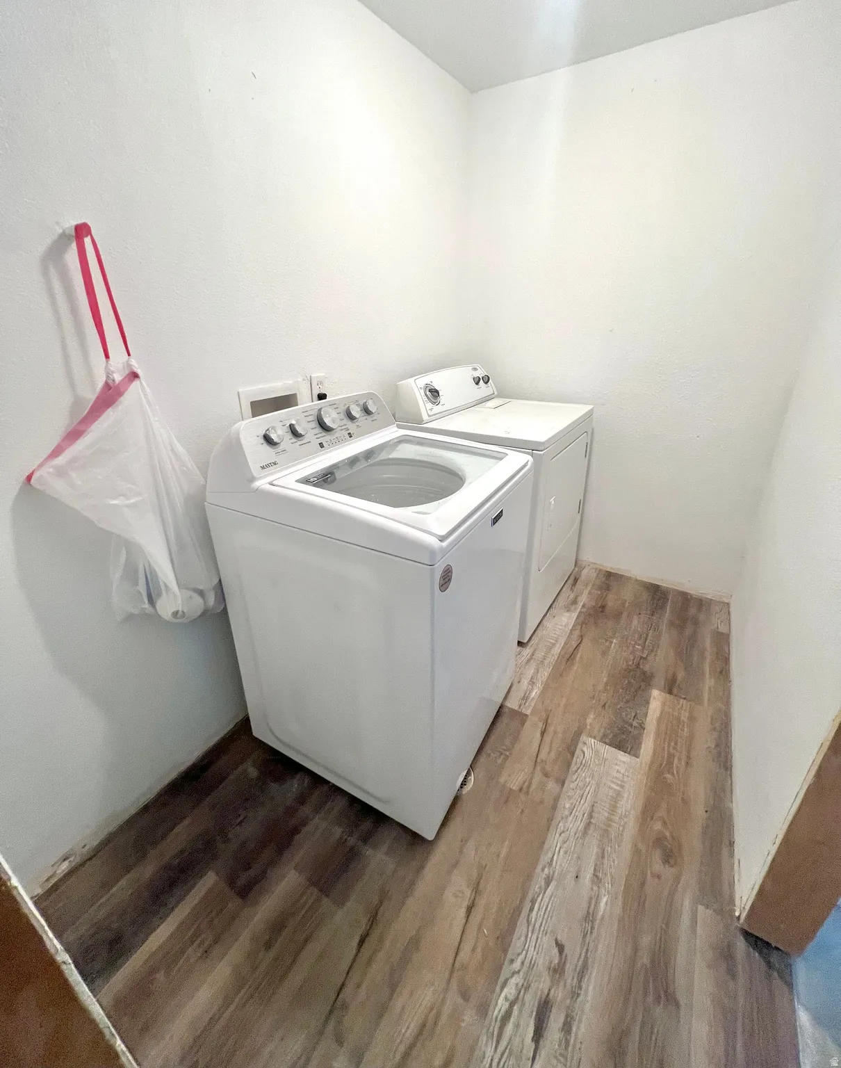 Dedicated laundry area featuring wood-finish flooring and white walls