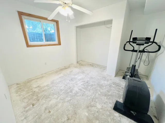 Room featuring a wood-trimmed window, a ceiling fan with light fixture, and a recessed alcove
