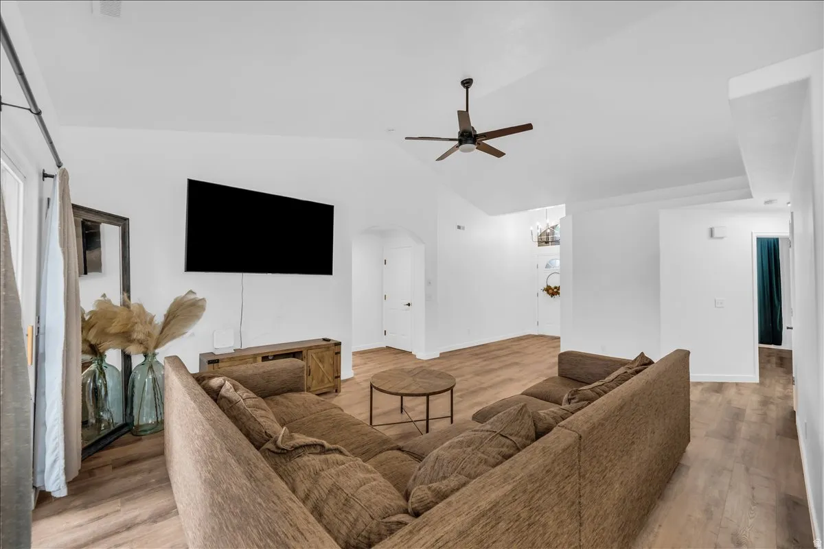 Spacious living area featuring vaulted ceilings, wood-finish flooring, and a ceiling fan