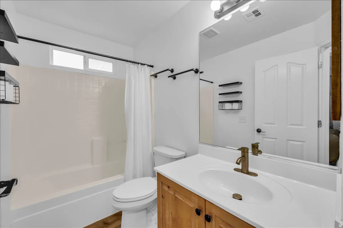 Full bathroom featuring a single vanity with wood-finish cabinetry, white countertop, and integrated sink