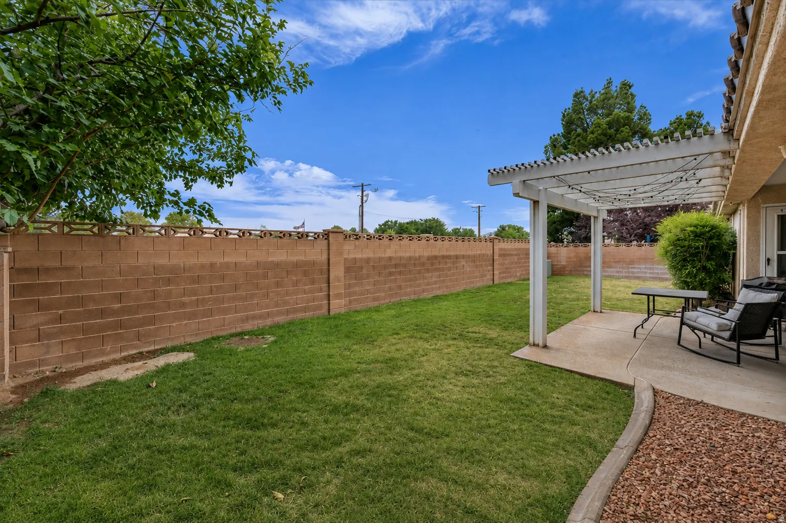 Spacious backyard featuring a large concrete patio with a white open-lattice pergola