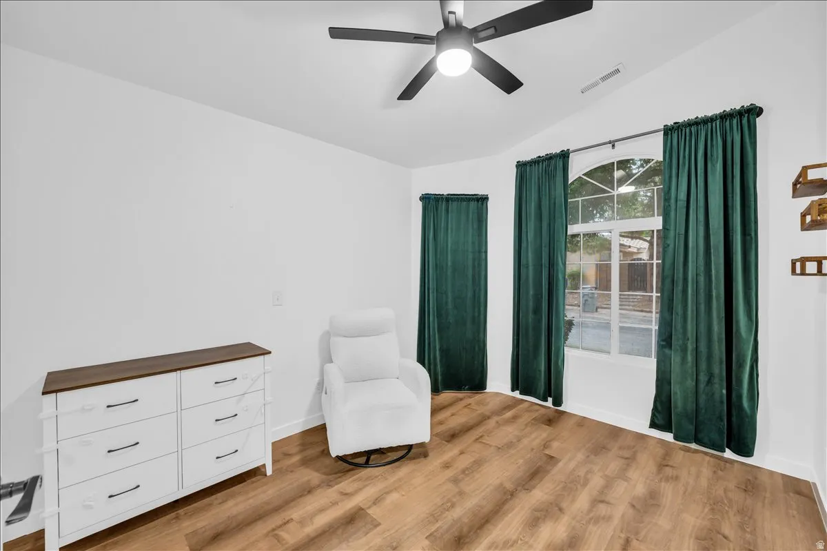 Vaulted ceiling room featuring wood-finish flooring, a contemporary ceiling fan, and an arched window