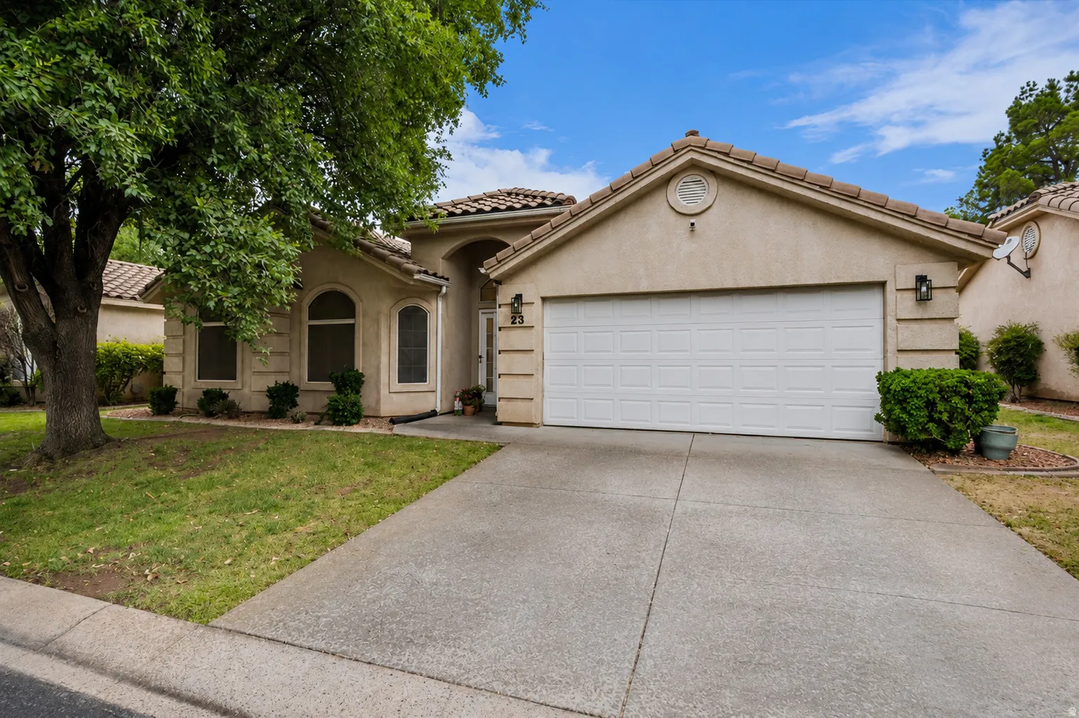 Stucco exterior featuring a tiled roof and an attached garage with a panel door