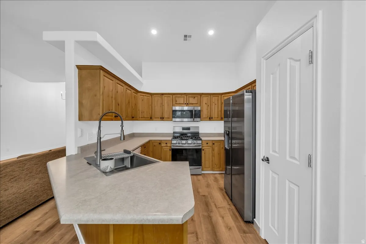 Kitchen featuring wood-finish cabinetry, light-toned countertops, and wood-finish flooring