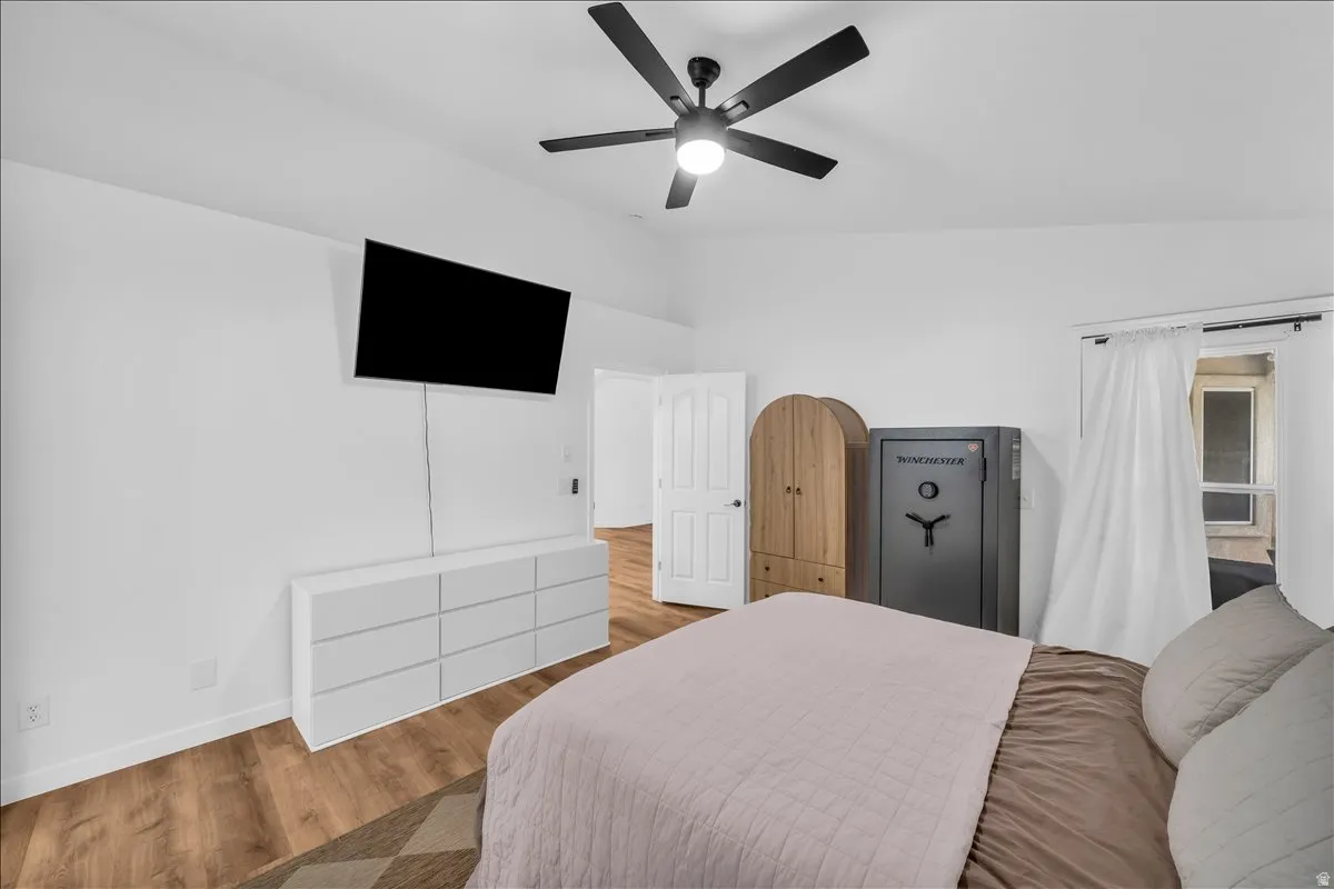 Spacious room featuring vaulted ceilings, wood-finish flooring, and a modern ceiling fan with integrated lighting