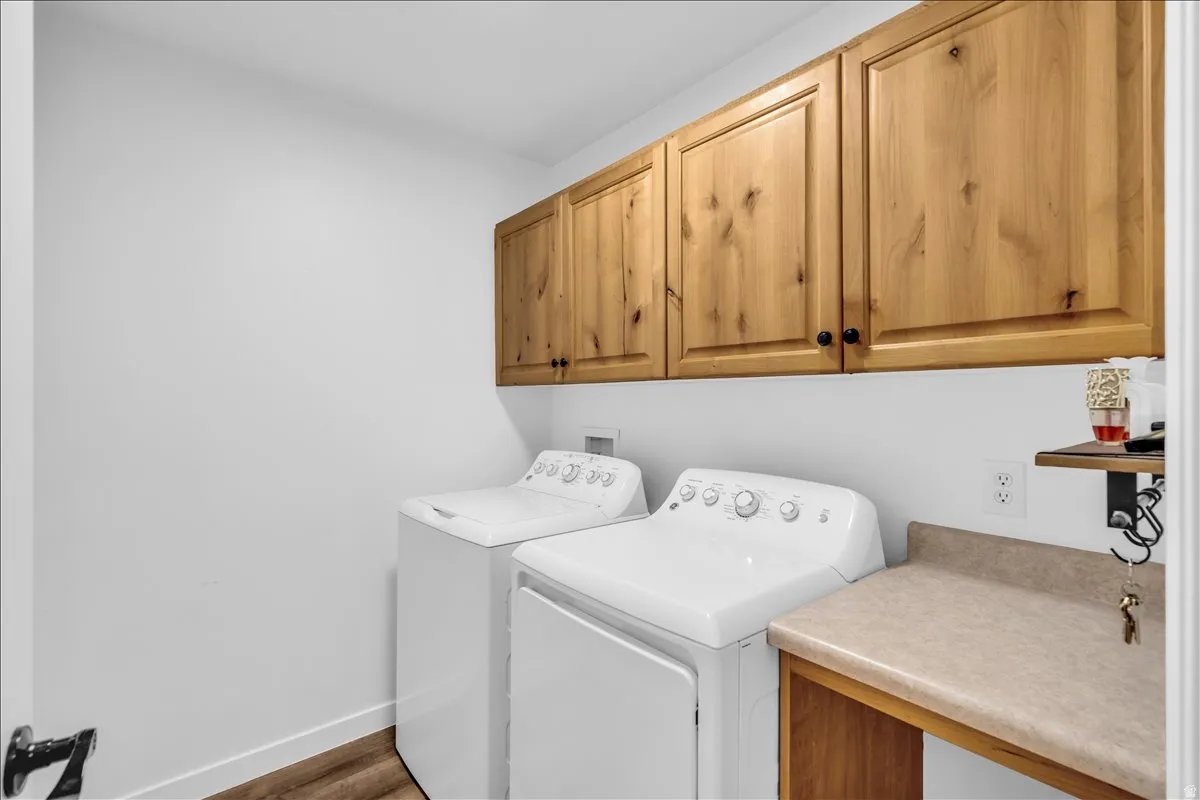 Laundry area featuring wood-finish cabinetry, a utility countertop, and wood-finish flooring