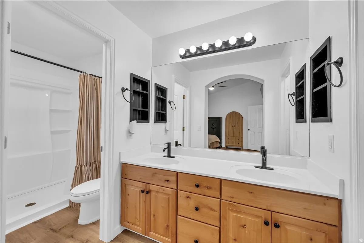 Dual sink vanity with light wood cabinetry, white countertops, and matte black fixtures