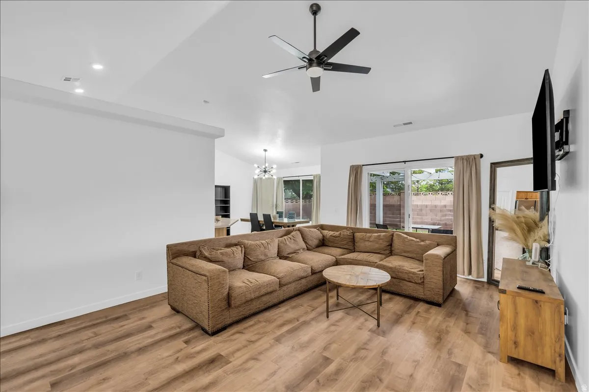 Spacious living area featuring wood-finish flooring, vaulted ceilings, and a ceiling fan