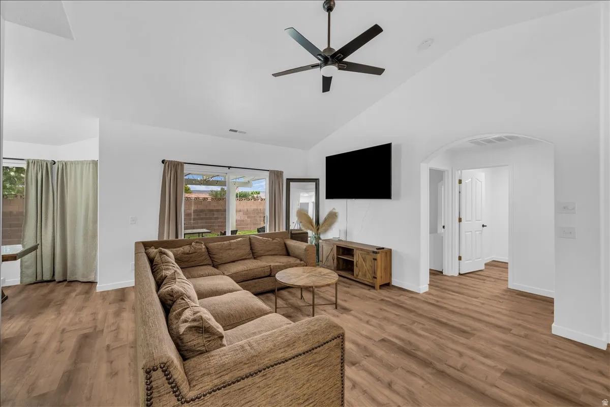 Spacious living area featuring wood-finish flooring, vaulted ceilings, and a ceiling fan
