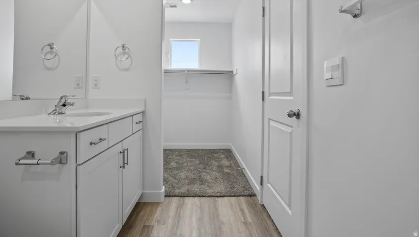 Vanity with integrated sink, white cabinetry, and a light-toned countertop