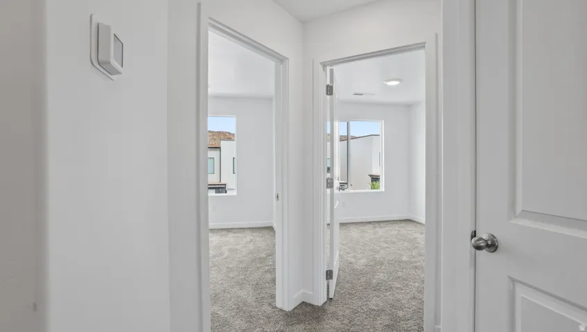 Bright interior hallway with a white panel door and modern wall-mounted thermostat