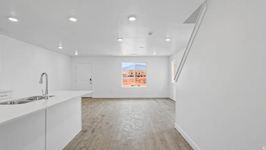 Open-concept living area featuring wood-finish flooring, recessed lighting, and a modern kitchen island with an undermount double-basin sink