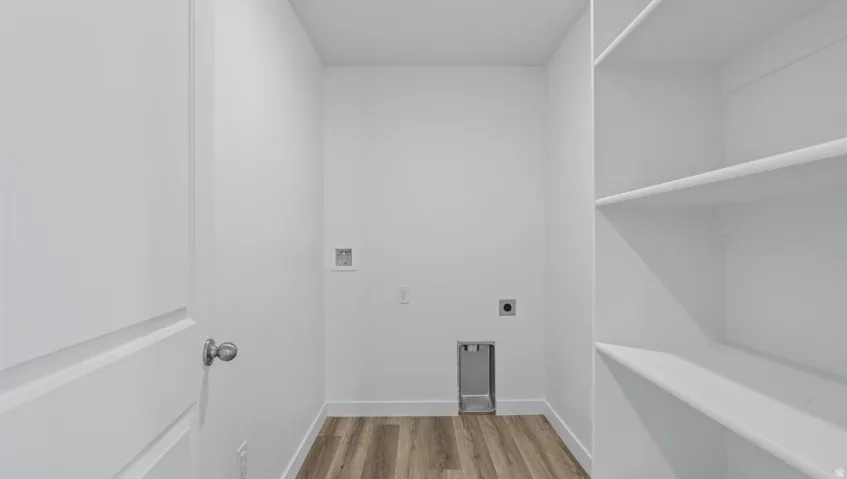 Laundry area featuring wood-finish flooring, white walls, and built-in shelving